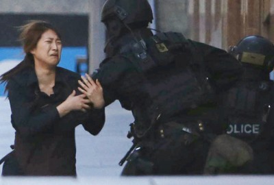 A hostage runs towards a police officer outside Lindt cafe, where other hostages are being held, in central Sydney
